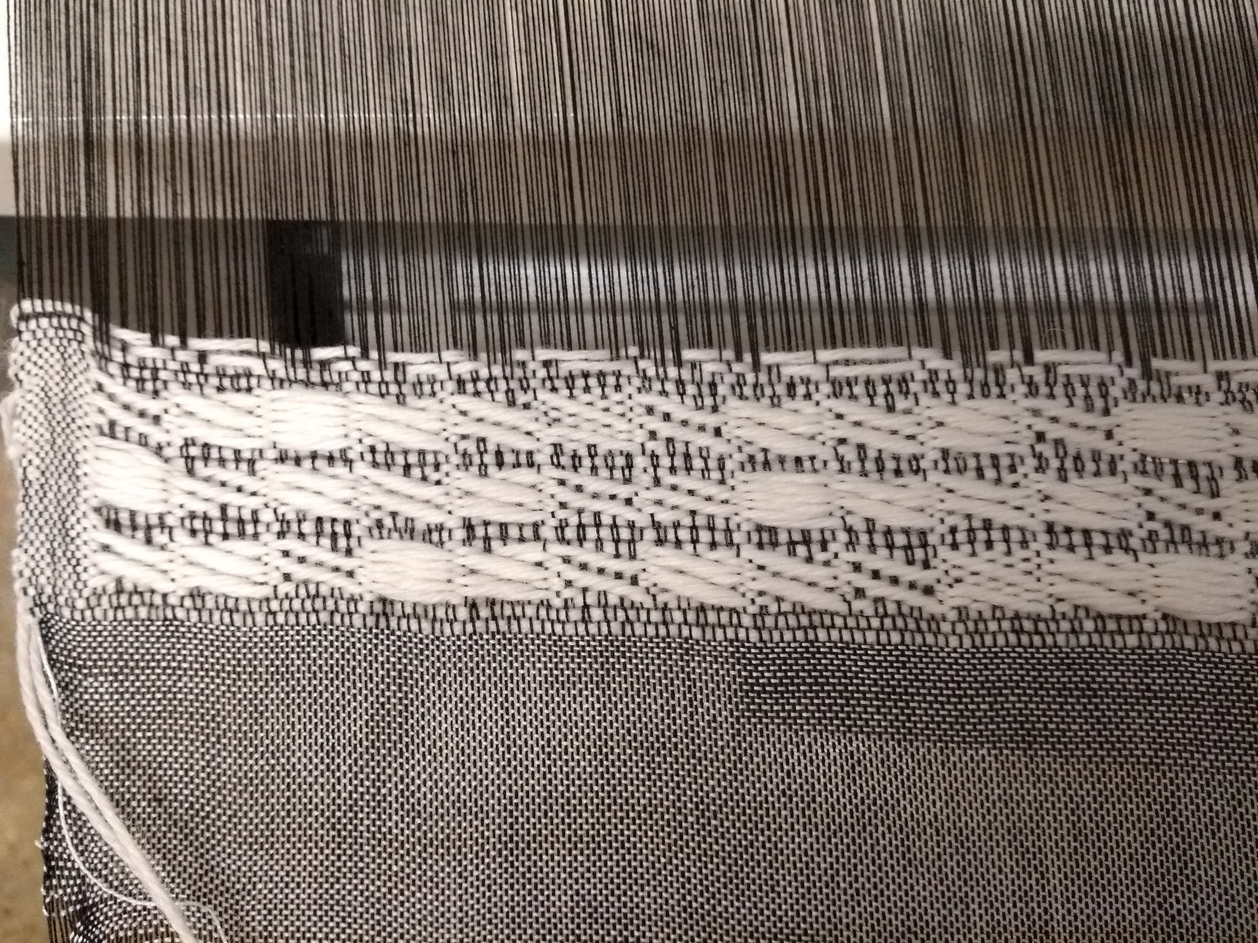 Detail of a black and white woven piece made using the Text to Weave draft.